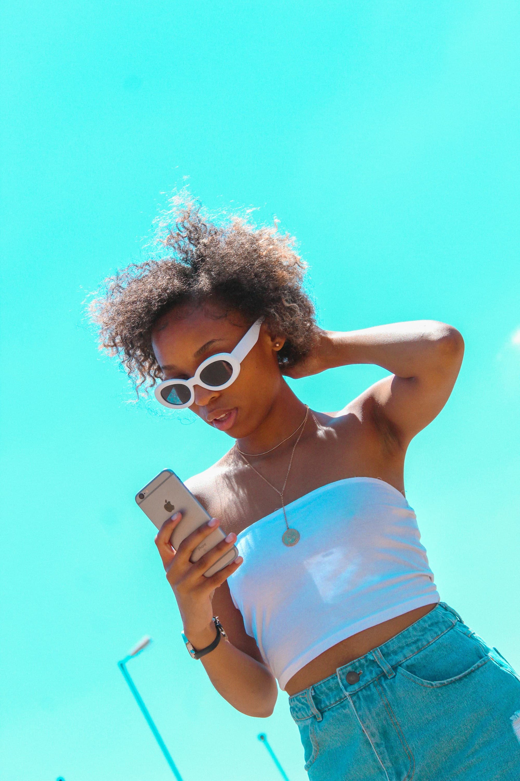 Mujer consultando su teléfono bajo un cielo azul
